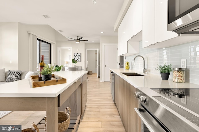 kitchen with white cabinets, light hardwood / wood-style flooring, sink, a breakfast bar, and appliances with stainless steel finishes