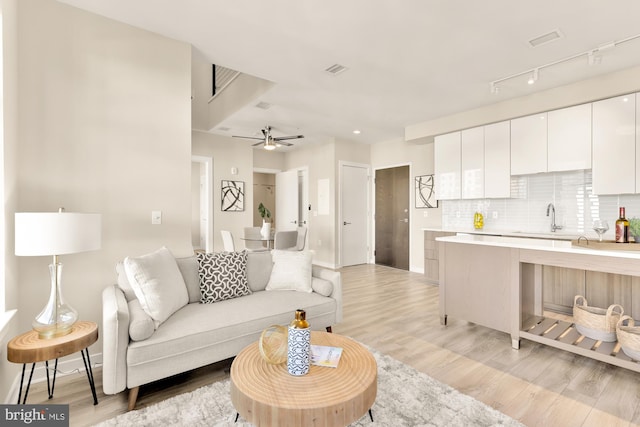 living room with light hardwood / wood-style flooring, ceiling fan, and sink