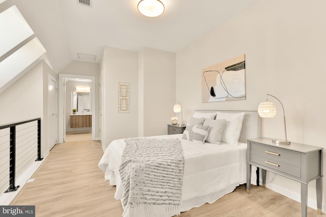 bedroom with light hardwood / wood-style floors and connected bathroom