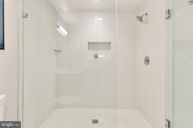 bathroom featuring a shower with door and toilet