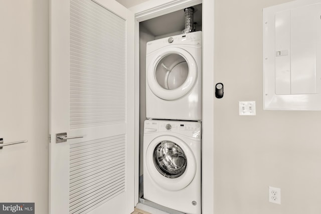 laundry area featuring stacked washer and clothes dryer and electric panel