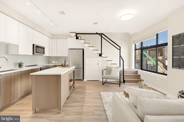 kitchen featuring white cabinetry, a kitchen island, appliances with stainless steel finishes, and light hardwood / wood-style flooring