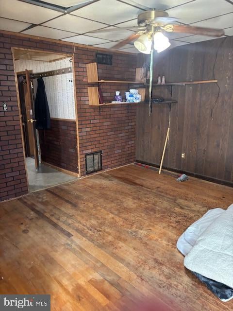 interior space featuring a paneled ceiling, wood walls, and wood-type flooring