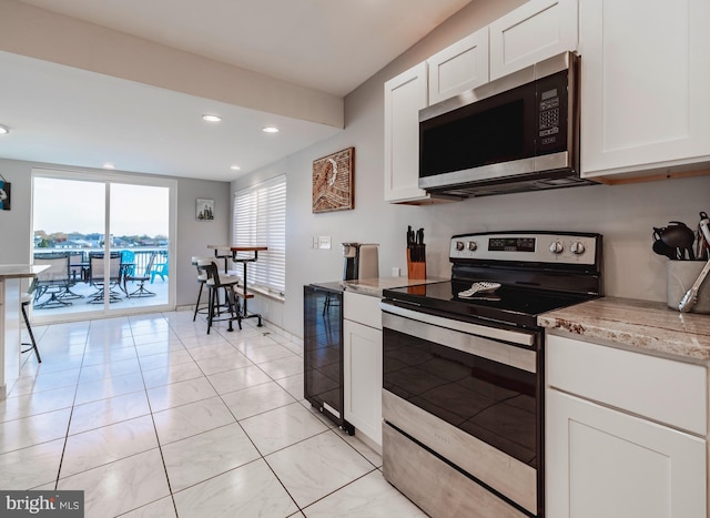 kitchen featuring stainless steel appliances, light stone countertops, white cabinetry, and beverage cooler