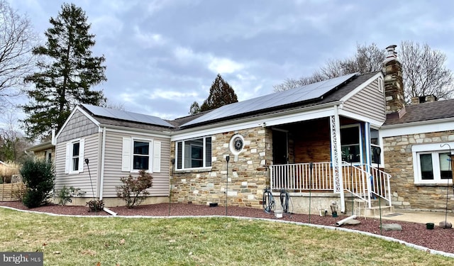 view of front of home featuring solar panels and a front yard