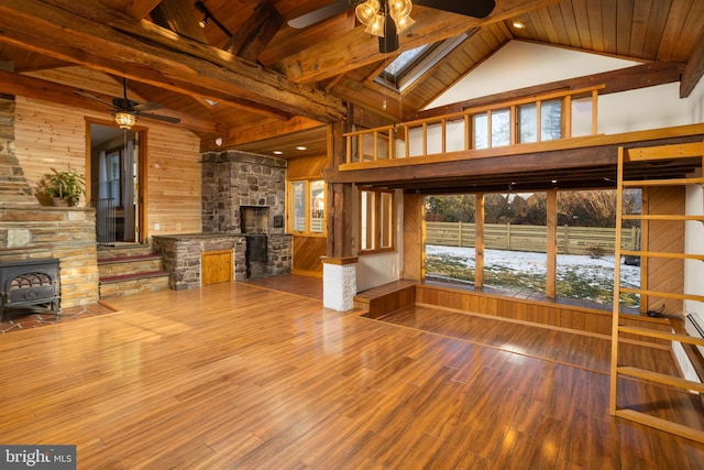 unfurnished living room with wood ceiling, wood walls, a skylight, beamed ceiling, and a wood stove