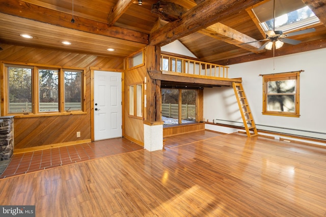 unfurnished living room with ceiling fan, wood-type flooring, wood walls, vaulted ceiling with skylight, and wood ceiling