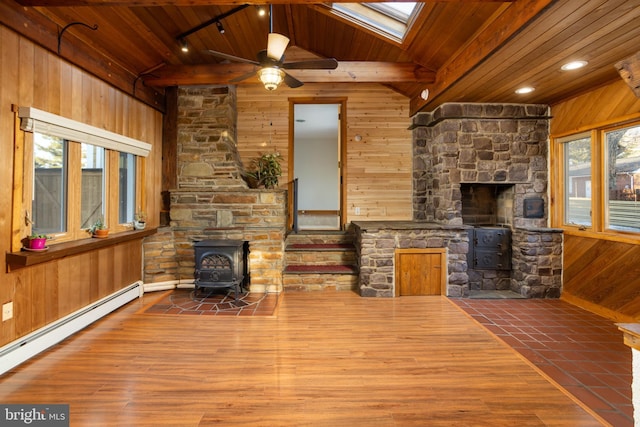 living room with wooden ceiling, wood walls, ceiling fan, a wood stove, and a baseboard heating unit