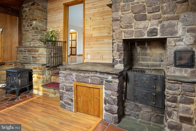 unfurnished living room featuring wood walls and a wood stove