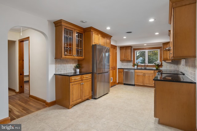 kitchen featuring sink, stainless steel appliances, dark stone countertops, and tasteful backsplash