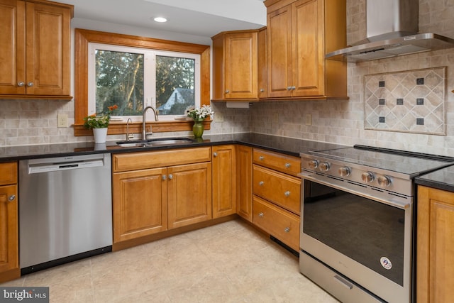 kitchen featuring sink, decorative backsplash, dark stone counters, wall chimney range hood, and appliances with stainless steel finishes