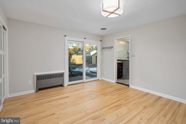 spare room featuring light wood-type flooring and radiator heating unit