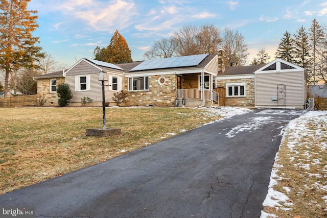 single story home with a porch, solar panels, and a yard