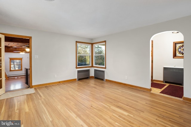 unfurnished living room featuring a baseboard heating unit, light wood-type flooring, and radiator