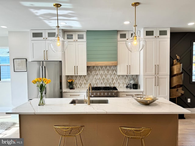 kitchen with an island with sink, white cabinetry, decorative light fixtures, and appliances with stainless steel finishes