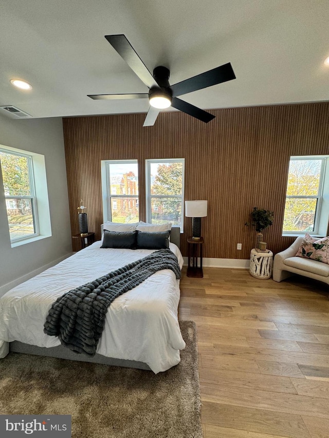 bedroom with ceiling fan, multiple windows, and light hardwood / wood-style floors