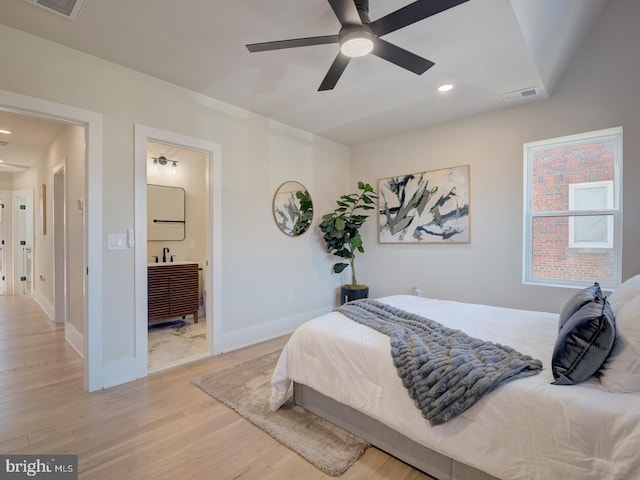 bedroom featuring light wood-type flooring, ceiling fan, and connected bathroom