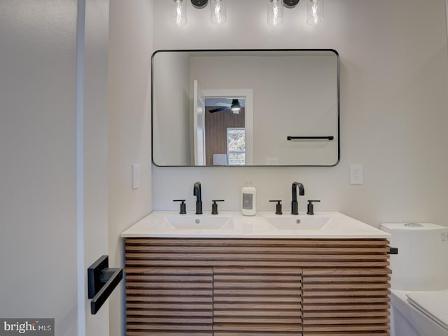 bathroom with toilet, vanity, and ceiling fan