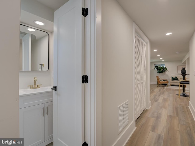 hall with sink and light wood-type flooring