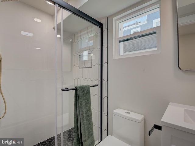 bathroom featuring toilet, vanity, and a shower with shower door