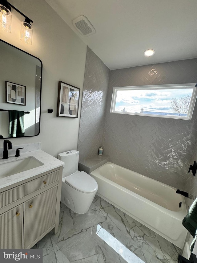 full bathroom featuring tiled shower / bath, vanity, and toilet