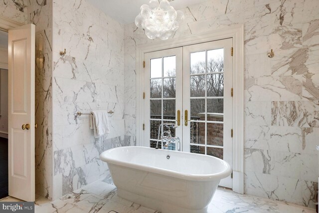 4825 Dexter Ter NW, Washington, DC 20007 - bathroom with french doors, a freestanding tub, marble tiled flooring, stone wall, and tile walls