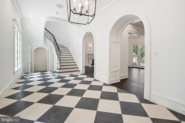 entrance foyer with dark hardwood / wood-style flooring, an inviting chandelier, and ornamental molding