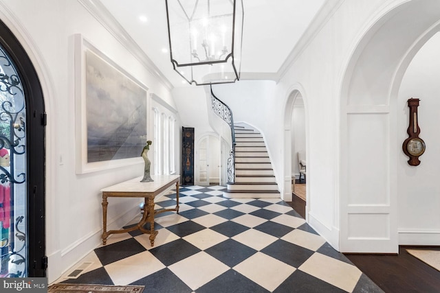 4825 Dexter Ter NW, Washington, DC 20007 - foyer entrance featuring arched walkways, stairs, a chandelier, ornamental molding, and baseboards