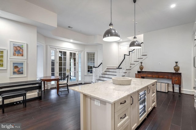 kitchen with pendant lighting, white cabinetry, dark wood-type flooring, and light stone counters