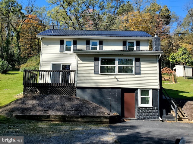 view of front of house featuring a front yard, a storage unit, and a wooden deck