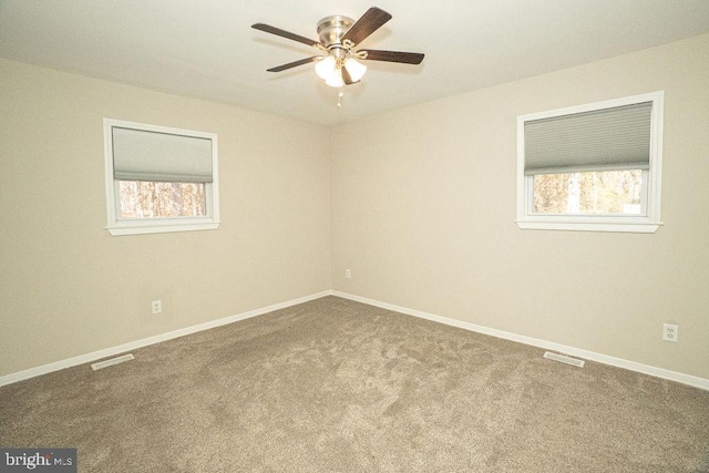 carpeted spare room with ceiling fan and plenty of natural light