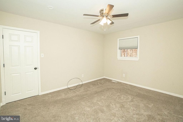 carpeted spare room featuring ceiling fan