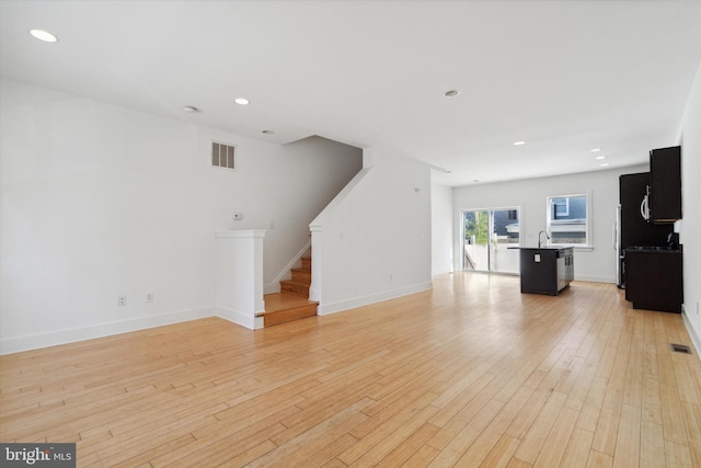 unfurnished living room with light hardwood / wood-style floors and sink