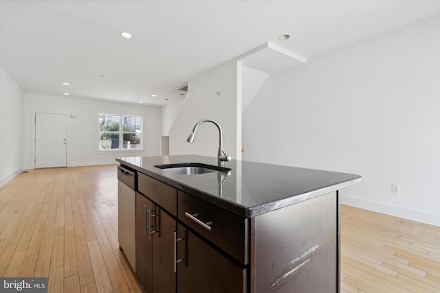 kitchen featuring a center island with sink, sink, stainless steel dishwasher, dark brown cabinets, and light hardwood / wood-style flooring