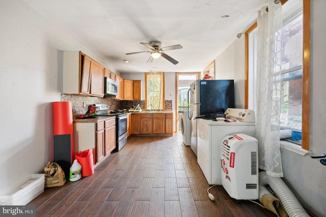 kitchen with stainless steel appliances, ceiling fan, dark hardwood / wood-style floors, washer / clothes dryer, and decorative backsplash