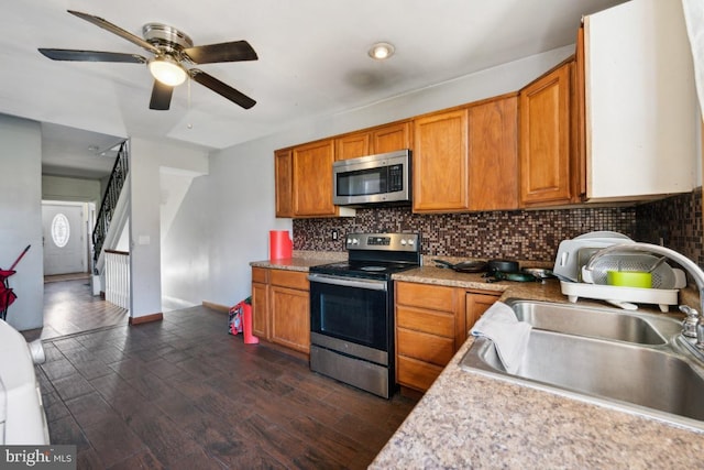 kitchen featuring stainless steel appliances, dark wood-type flooring, decorative backsplash, sink, and ceiling fan