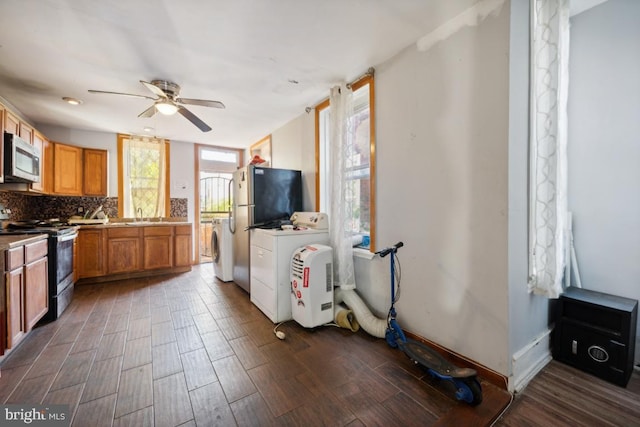 kitchen with tasteful backsplash, washer / dryer, stainless steel appliances, dark wood-type flooring, and ceiling fan