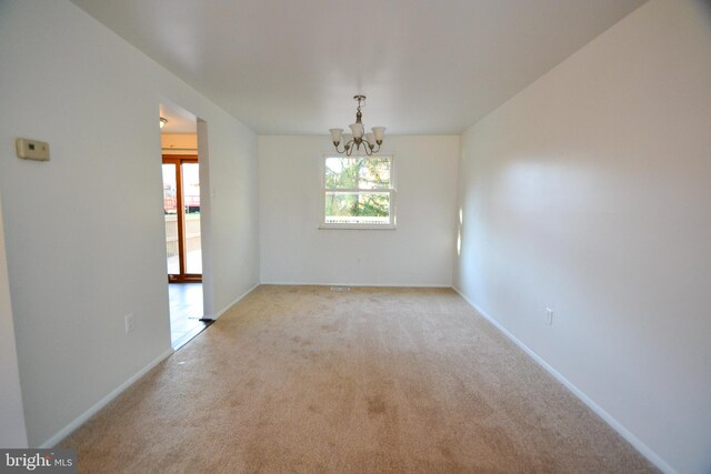 carpeted empty room with a chandelier