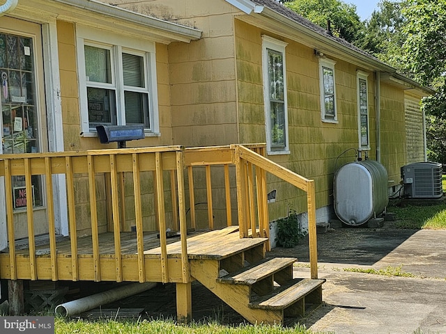 view of exterior entry with central air condition unit and a wooden deck