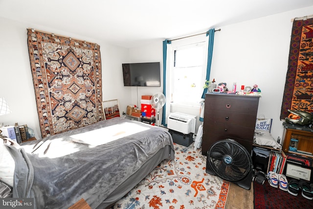 bedroom with light wood-type flooring and a wall mounted air conditioner