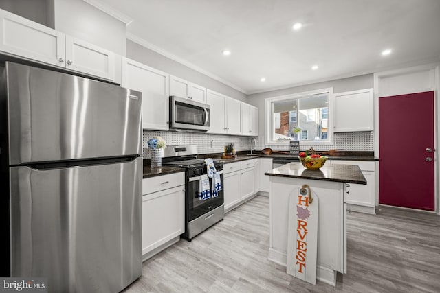 kitchen with ornamental molding, stainless steel appliances, light hardwood / wood-style floors, white cabinets, and a center island