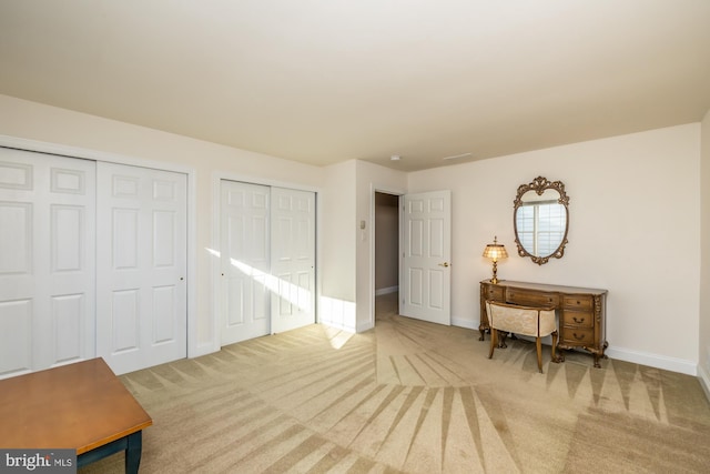 bedroom with multiple closets and light colored carpet