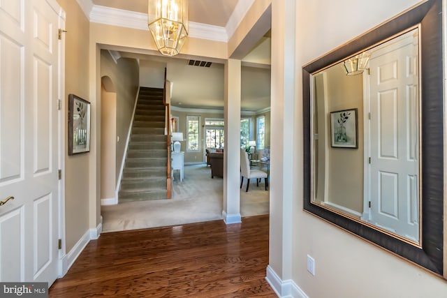 foyer with dark hardwood / wood-style floors, ornamental molding, and an inviting chandelier