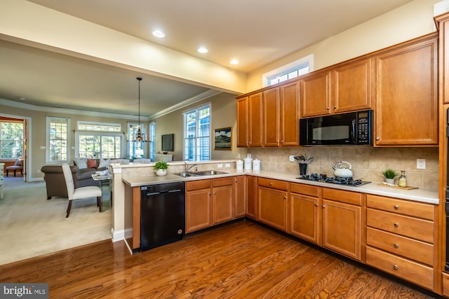 kitchen with hanging light fixtures, dark wood-type flooring, kitchen peninsula, black appliances, and ornamental molding