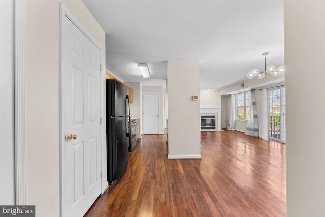 kitchen with stainless steel electric range, black refrigerator, hanging light fixtures, dark wood-type flooring, and a chandelier