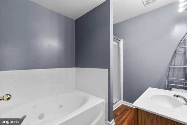 bathroom with wood-type flooring, vanity, and plus walk in shower