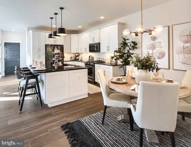 kitchen featuring dark hardwood / wood-style flooring, white cabinetry, appliances with stainless steel finishes, and hanging light fixtures