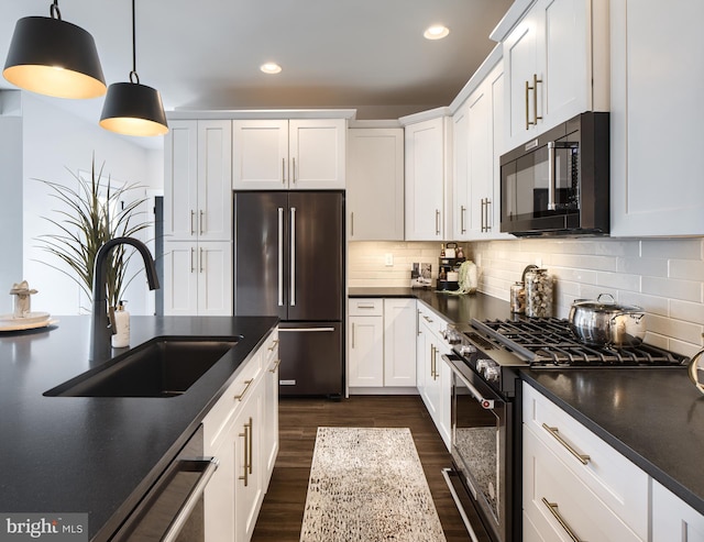 kitchen with hanging light fixtures, white cabinetry, premium appliances, and sink