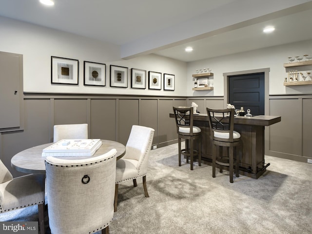 carpeted dining room featuring bar and beam ceiling