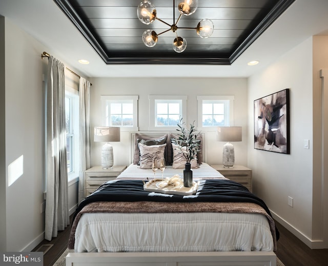 bedroom featuring dark wood-type flooring, ornamental molding, and a raised ceiling